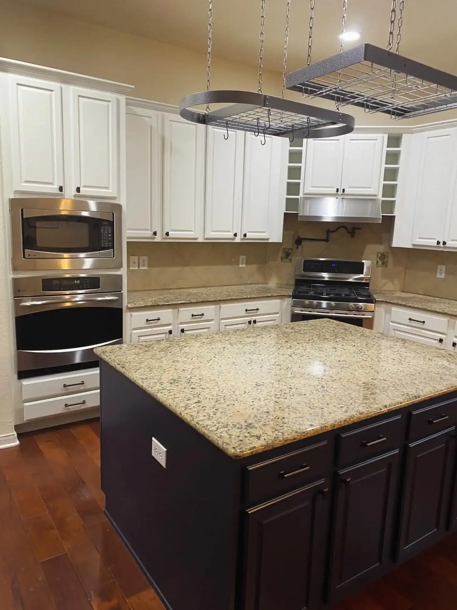 White and Dark Cabinet Kitchen Remodel White painted upper cabinets with dark painted island and granite countertop in modern kitchen with stainless steel